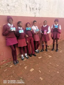 A happy group of young school girls at a school holding up their free sanitary pads