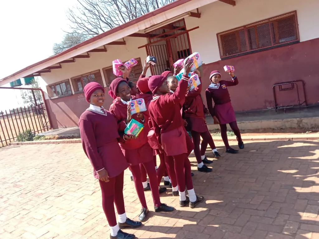 A happy group of young school girls at a school holding up their free sanitary pads