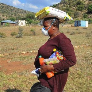 Village woman carrying groceries in her hands and on her head