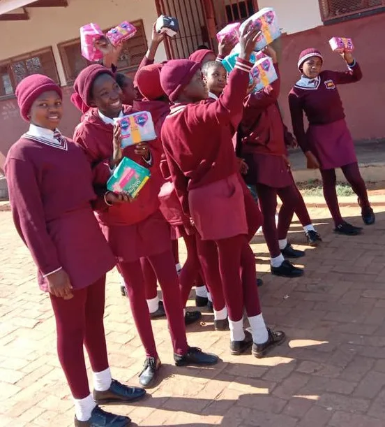 A happy group of young school girls at a school holding up their free sanitary pads