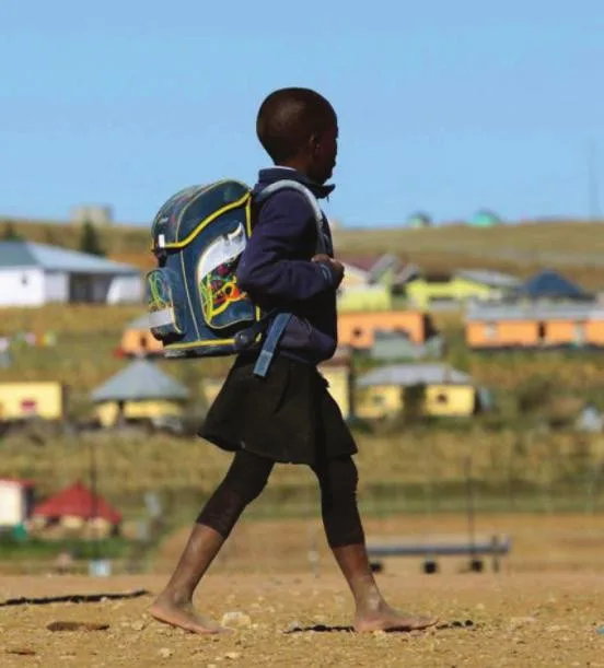 A young school child walking in a rural village without shoes